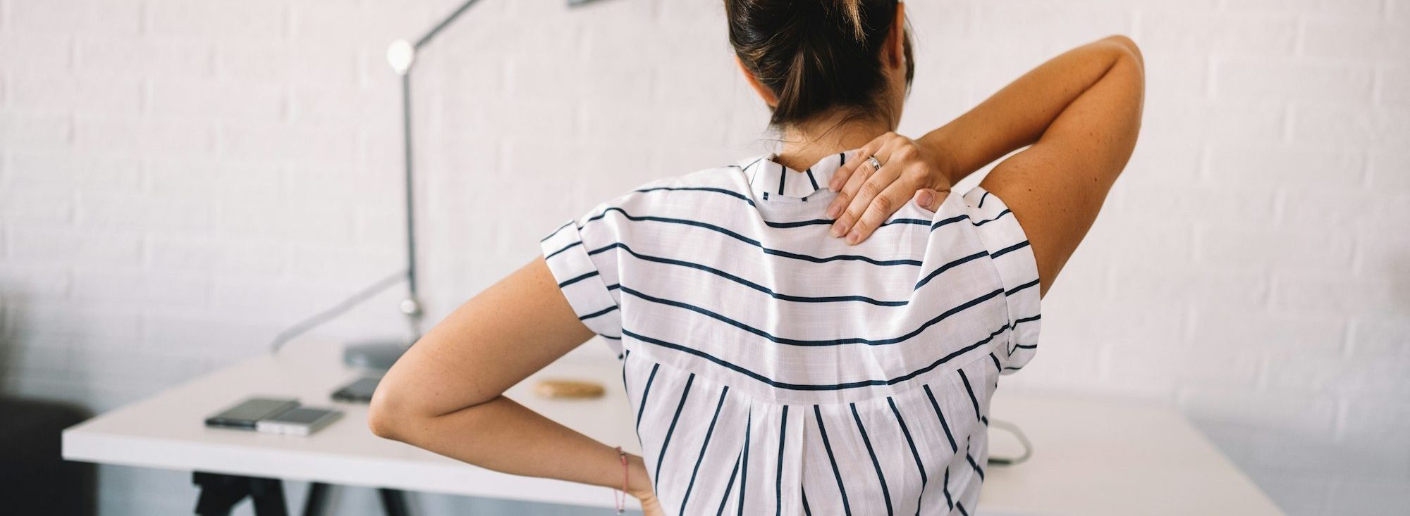 Overworked woman with back pain in office with bad posture